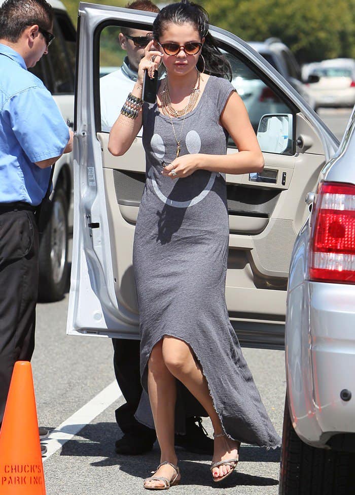 Selena Gomez wearing an asymmetrical dress with a smiley print from the brand Sauce