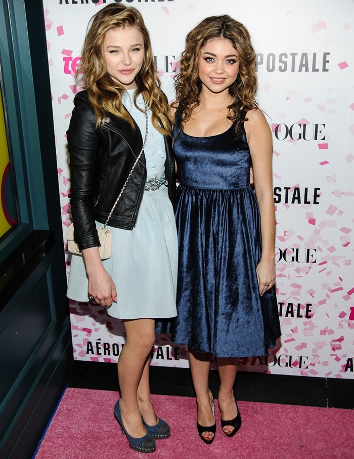Sarah Hyland wears a dress by alice + olivia by Stacey Bendet while posing with Chloë Grace Moretz
