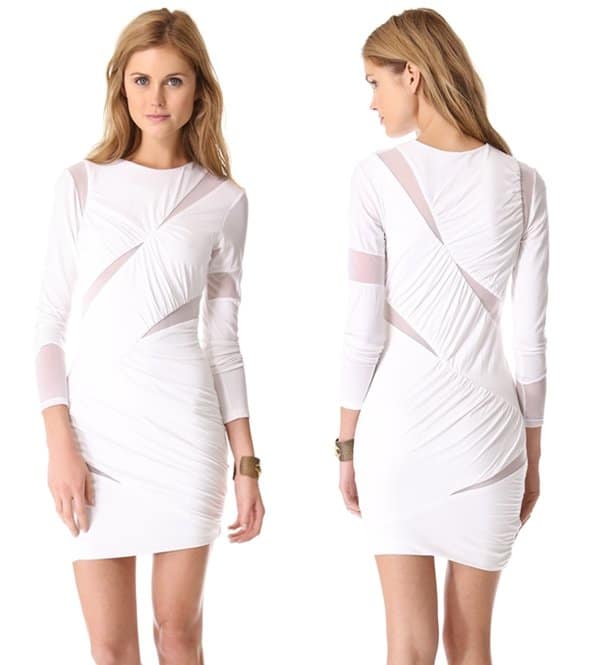 Mesh-lined cutouts slash across a formfitting white jersey dress, which gains a relaxed texture from ruching and pleats