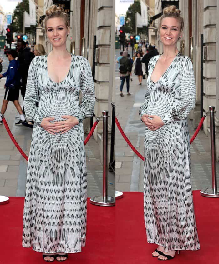 Julia Stiles protectively holding her baby bump in a sweater maxi dress on the red carpet