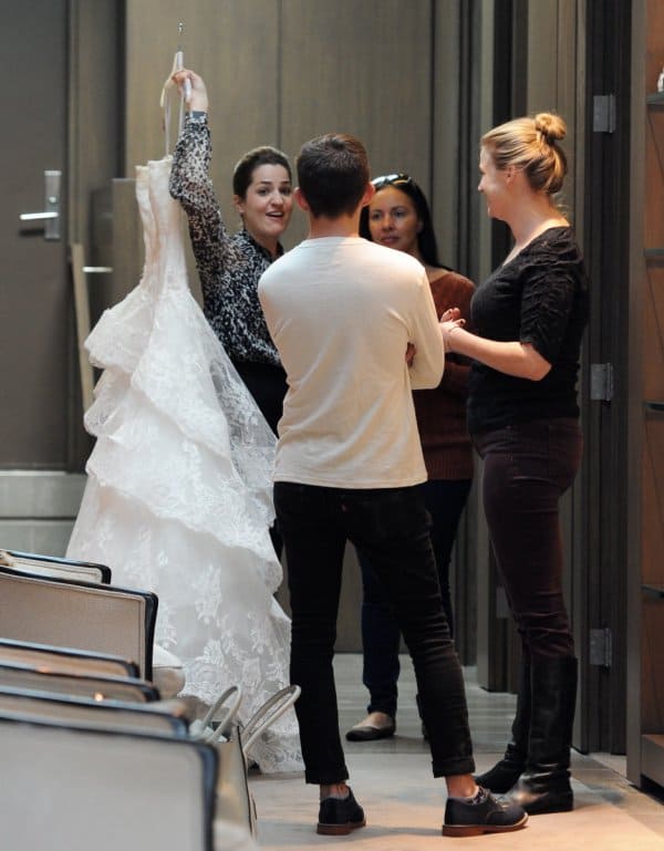 A wedding gown consultant holds up a gown for Naya to try