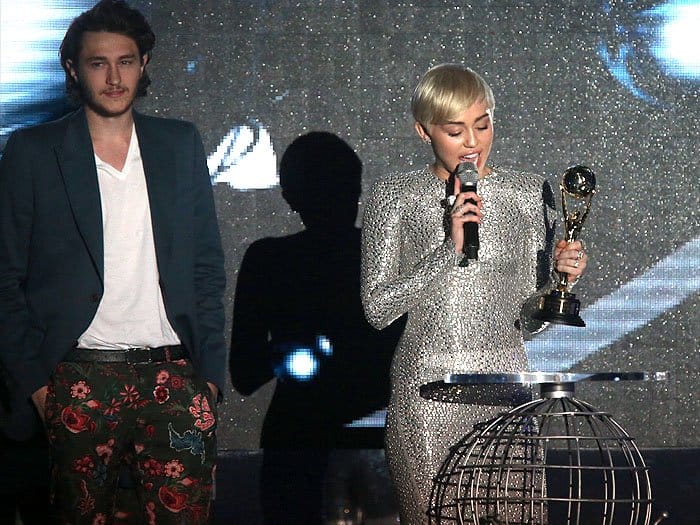 Miley Cyrus accepting her award on stage at the 2014 World Music Awards with younger brother Braison Cyrus