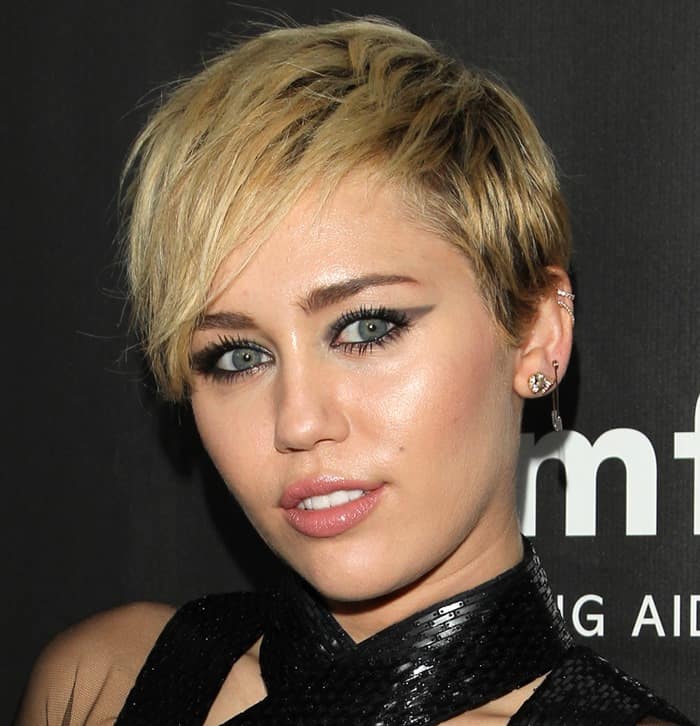 At the 2014 amfAR Gala, Miley Cyrus elevated her bold platinum pixie cut with a striking gray smoky cat eye, thick mascara, and a shiny nude lip