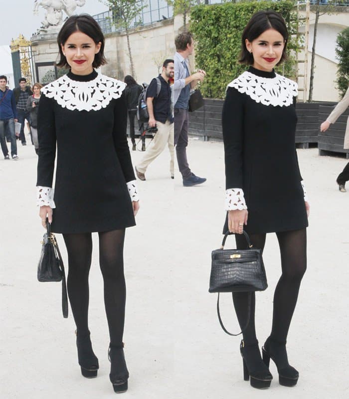 Miroslava Duma in a black and white outfit adorned with a white lace overlay and complemented with coordinating black accessories at the Viktor & Rolf show