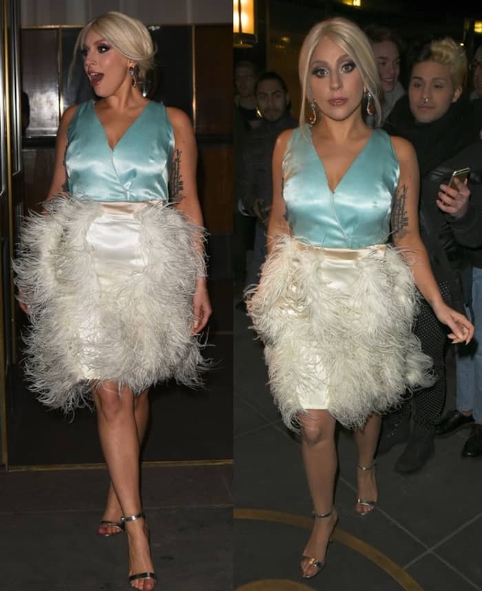 Lady Gaga flaunts her legs in a plunging sleeveless satin crop top paired with a fur-fringed white skirt and silver strappy heels