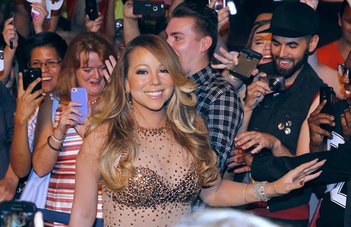 Mariah Carey wearing a floor-grazing high neck nude mesh gown featuring shimmering gold embellishments