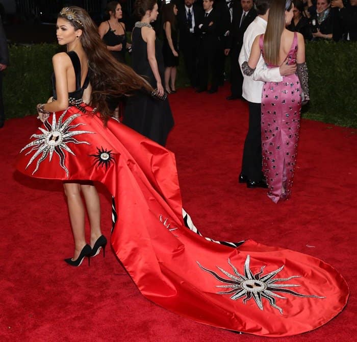 Zendaya donned a captivating dress by Fausto Puglisi featuring a hand-embroidered sun motif, a plunging black velvet bodice, and a crimson silk duchesse asymmetric skirt