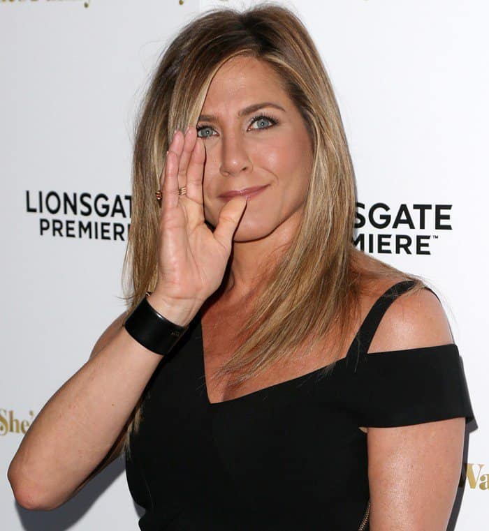 Jennifer Aniston wearing a black jumpsuit and showing off her post-honeymoon tan and new wedding ring