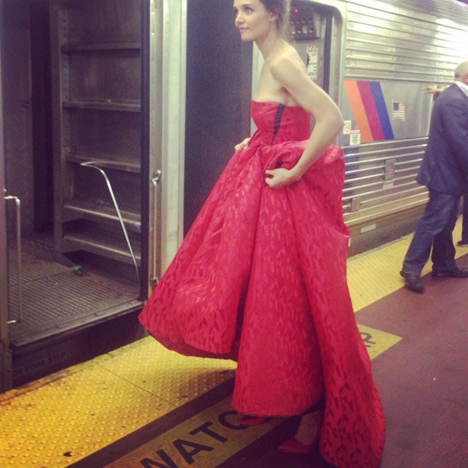 Katie Holmes shared a cute photo where she was seen hiking up a stunning strapless red gown and sporting matching red heels at Penn Station in New York City