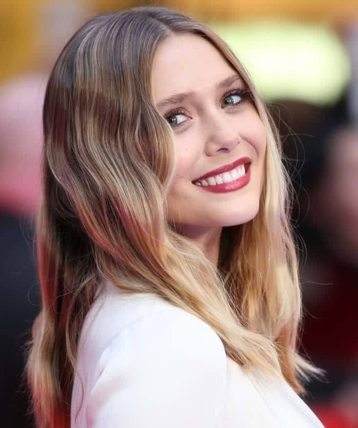 Elizabeth Olsen elegantly fashioned her blonde hair into cascading loose waves and sported a striking red lip