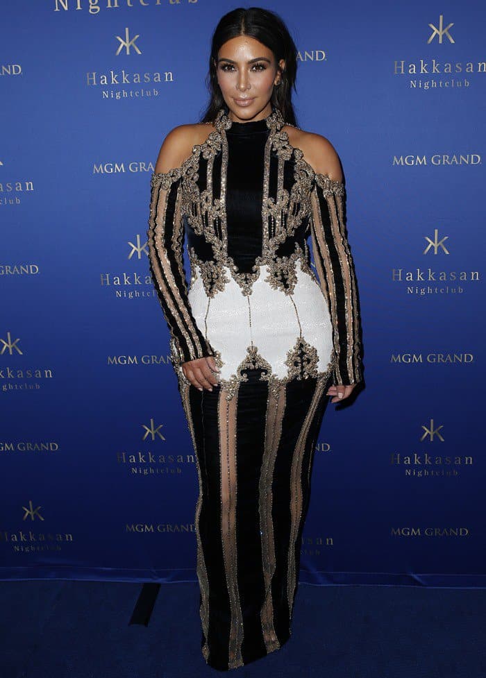 Kim Kardashian poses on the carpet in a gold-embellished Balmain dress