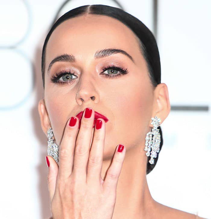 Katy Perry opted for a sleek, slicked-back chignon hairstyle, elegantly showcasing her Harry Winston earrings