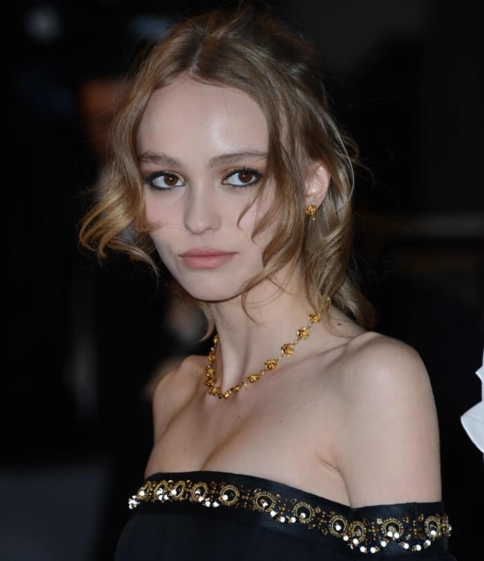 Lily-Rose Depp's honey blonde tresses were skillfully gathered into an elaborate chignon, allowing delicate curls to frame her enchanting visage