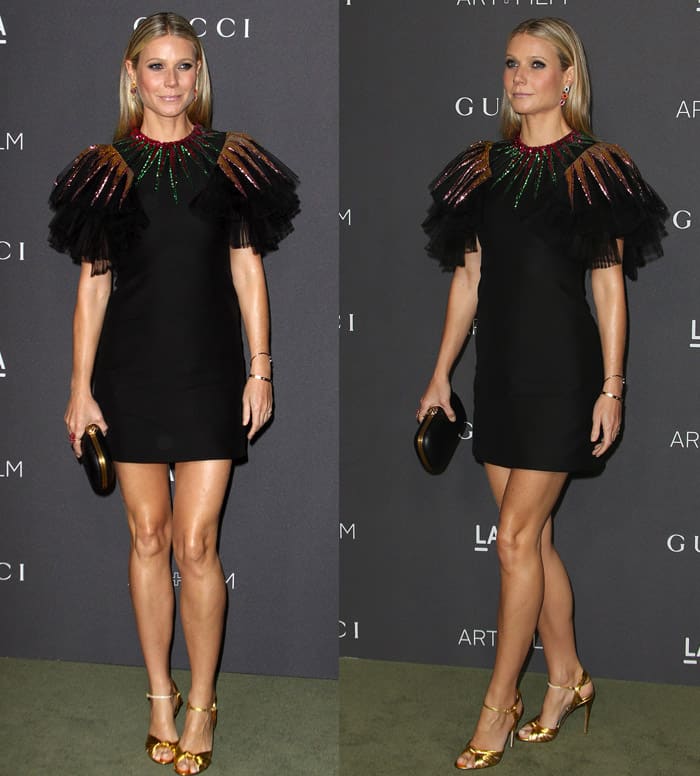 Gwyneth Paltrow flaunts her legs in a unique black Gucci dress adorned with sun blades on the neck and shoulders in hues of brown, green, and red