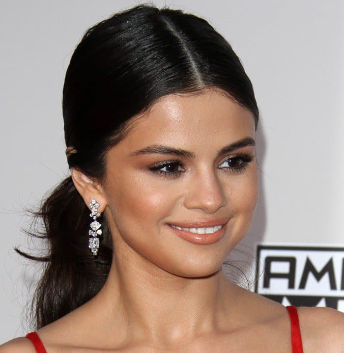 Selena Gomez's hairstyle choice to show off her sparkly dangly earrings was a sleek, center-parted low ponytail