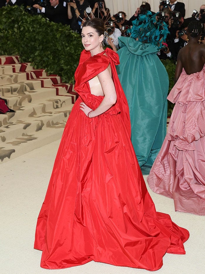 Anne Hathaway in a red Valentino ruffled halter ball gown and a gold spiked halo.
